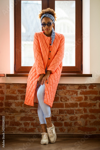 African model woman in orange spring jacket and blue pants photo