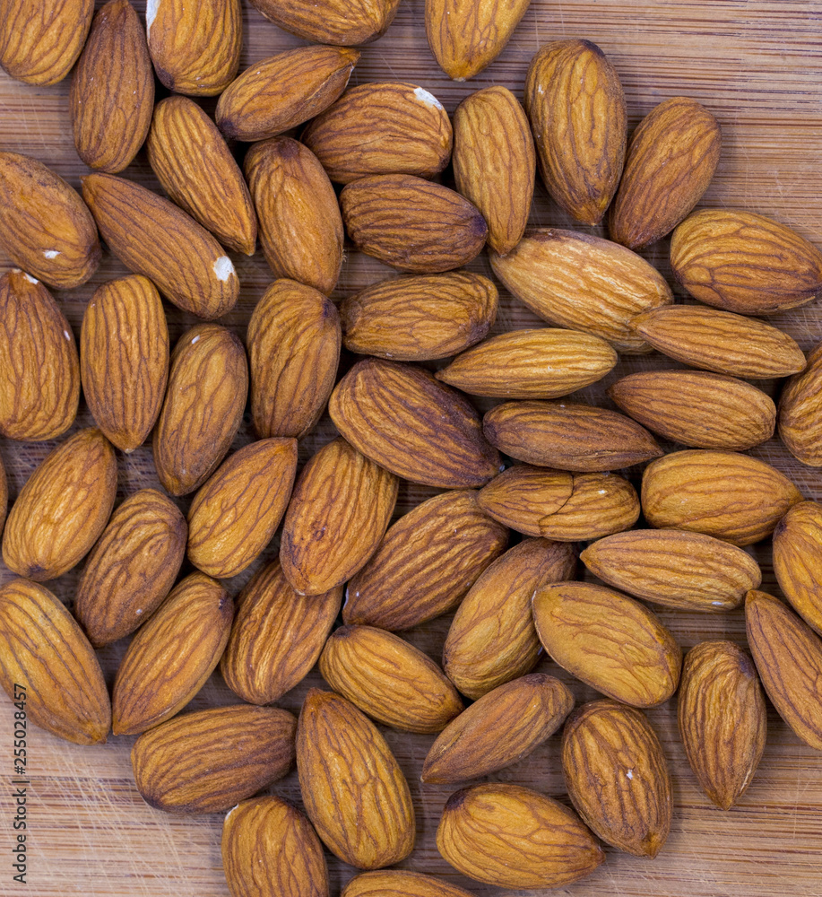 Fototapeta premium Almond nuts on timber background, top view photo. Tasty healthy snack. Scattered nuts on table