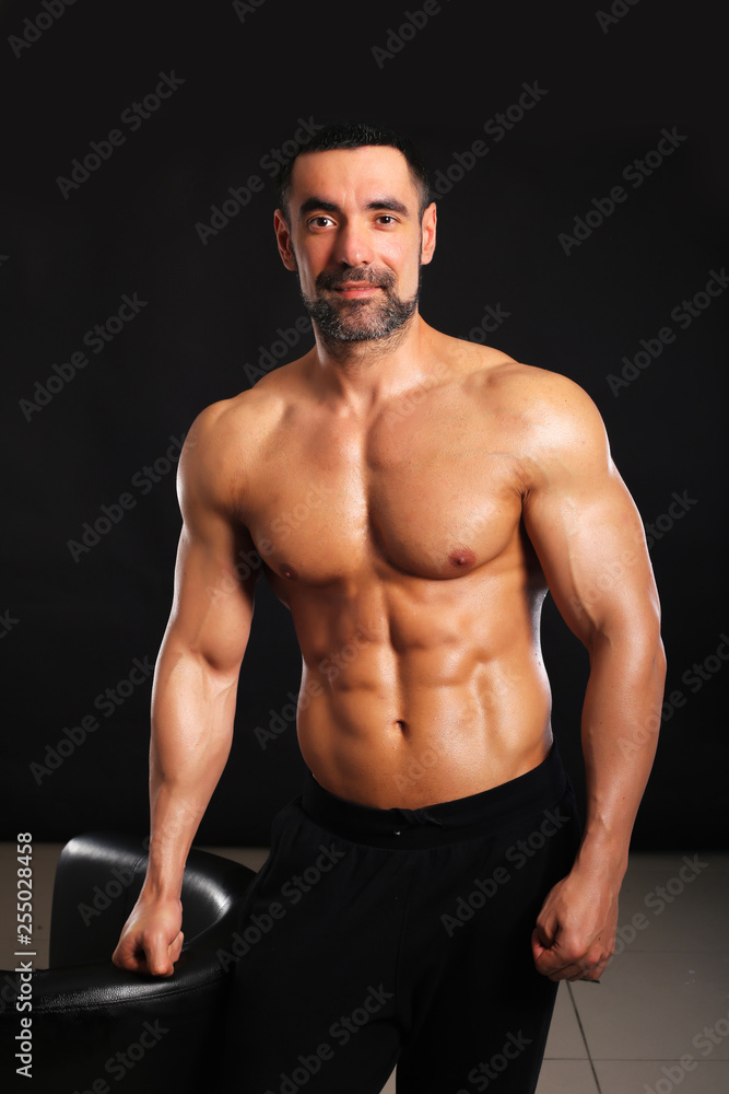 Fototapeta premium Portrait of smily young bodybuilder on black background in t shirt 