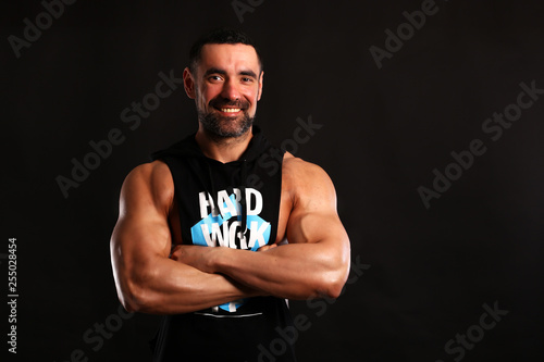 Portrait of smily young bodybuilder on black background in t shirt 