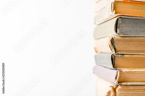 A stack of old books. Yellow frayed pages. Worn damaged book covers. Book store or e-books.