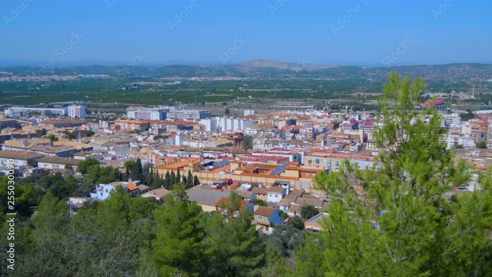 Small provincial town at the foot of the mountains in Spain. The orange color tile of roofs the houses are clearly visible from the mountain. The walls of the ancient castle descend from the mountains Small provincial town at the foot of the mountains in Spain. The orange color tile of roofs the houses are clearly visible from the mountain. The walls of the ancient castle descend from the mountains