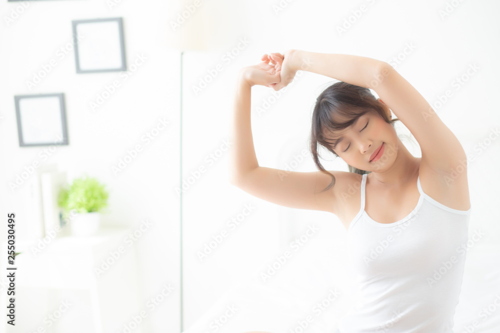Beautiful of portrait young asian woman stretch and relax in bed after wake up morning at bedroom, new day and resting for health and wellness, back view, lifestyle concept.