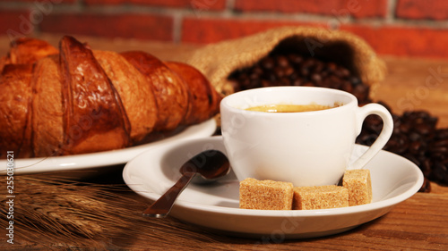 Coffee white cup  croissants on wooden table and roasted coffee beans. Breakfast concept