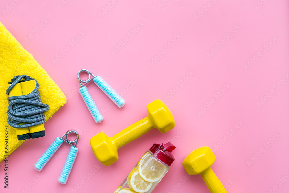 Fitness set with bars, towel, bottle of water and wrist builder on pink background top view mock up Fitness set with bars, towel, bottle of water and wrist builder on pink background top view mock up