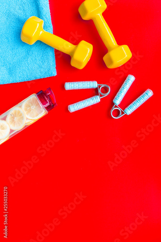 Sport with bars, towel, water and wrist builder red background top view space for text