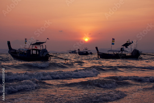 Long-tailed boat in wavy sea during sunset at Khlong Muang Beach, Krabi, Thailand. © grit.wattanapruek