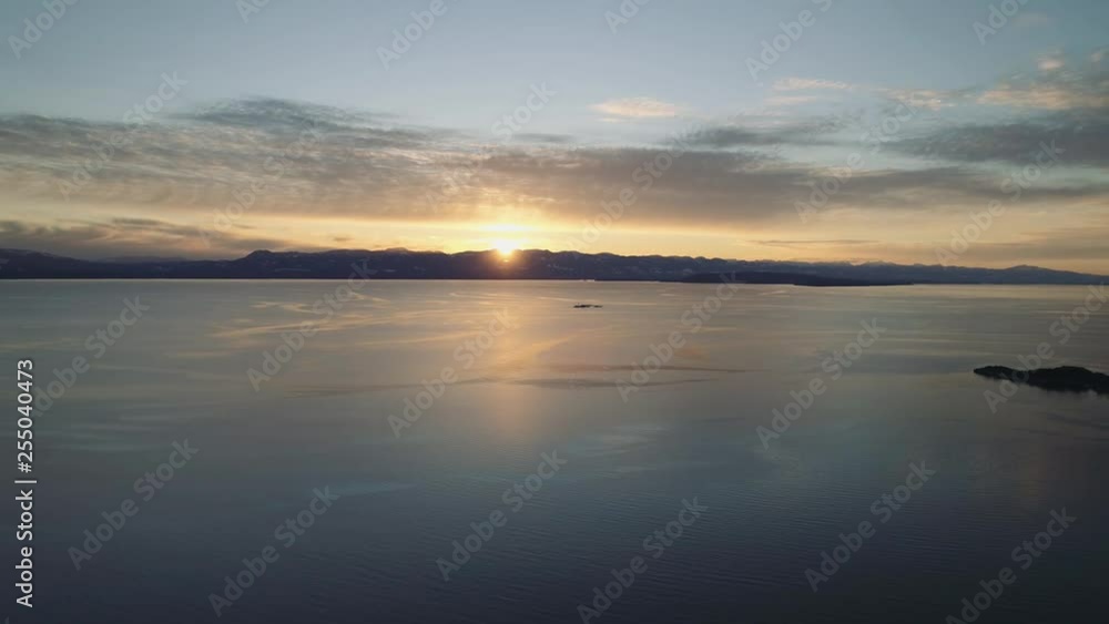 Aerial shot just before sunset over wide expanse of water. Mountains in the distance with islands below. Majestic scenery. Aerial shot just before sunset over wide expanse of water. Mountains in the distance with islands below. Majestic scenery.