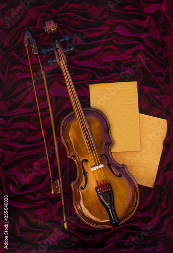 Canvas Print Violin, fiddlestick and two sheets on red cloth