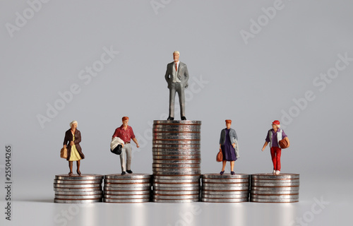 Miniature people with stack of coins. A concept of income inequality.