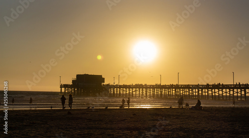 Sunset on California beach as people play in beach © dcorneli