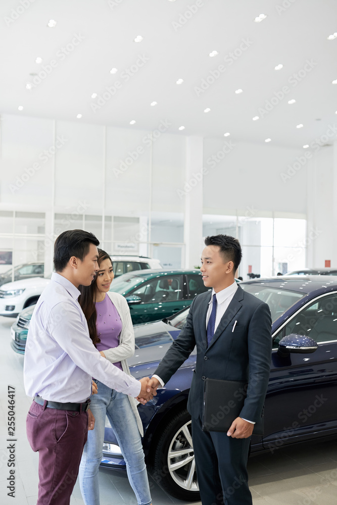 Salesman meeting clients in car dealership Salesman meeting clients in car dealership