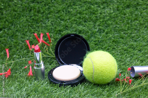 Tennis ball and cosmetic lipstick and powder for lady woman tennis player on green grass