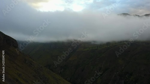 Epic aerial of a grassy mountain in the Andes with low hanging clouds