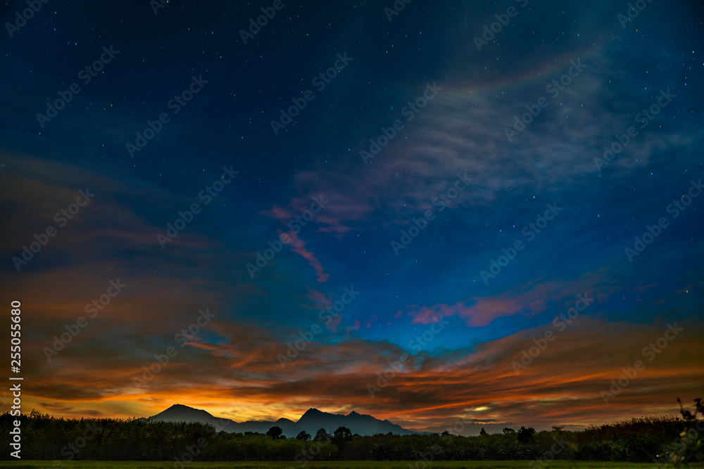 Dark starry sunset sky with mountains on horizon. Twilight sky with many stars on the sky.