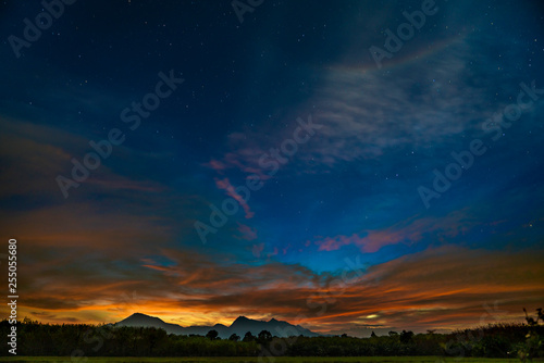 Dark starry sunset sky with mountains on horizon. Twilight sky with many stars on the sky.