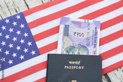 Closeup of Indian passport with currency on USA or america's flag as a background photo