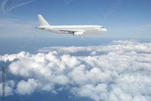 White passenger airplane is flying over the cloudy sky.