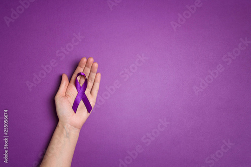 Hand holding Purple ribbons on a p urple background. World epilepsy day. photo