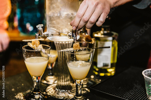 Bartender pouring absinthe into cocktail glasses during an evening holiday event.   photo
