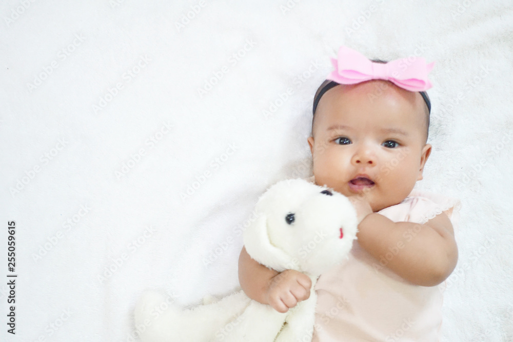 Newborn baby girl hug and cuddling her dog doll on white background Newborn baby girl hug and cuddling her dog doll on white background