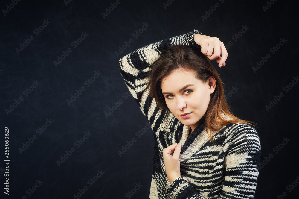 Studio portrait of a young woman on a dark background . The girl is dressed in a warm knitted sweater Studio portrait of a young woman on a dark background . The girl is dressed in a warm knitted sweater