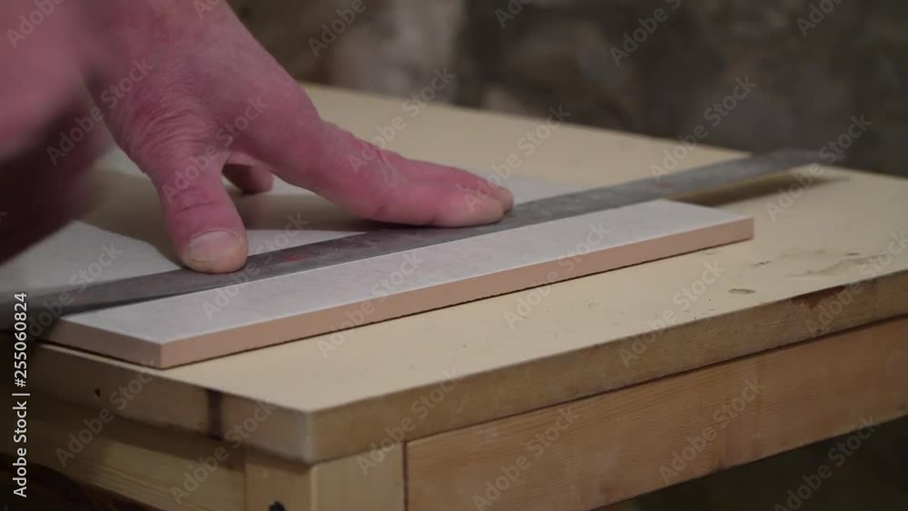 Worker with a hand cutter cuts tile. Finishing works, focus on hands. The technology of laying tile. Worker with a hand cutter cuts tile. Finishing works, focus on hands. The technology of laying tile.