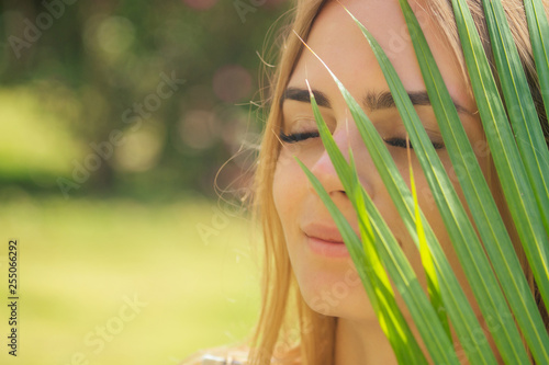 Картината върху платно close up portrait face blond woman thick eyebrows like Cara Delevingne with palm