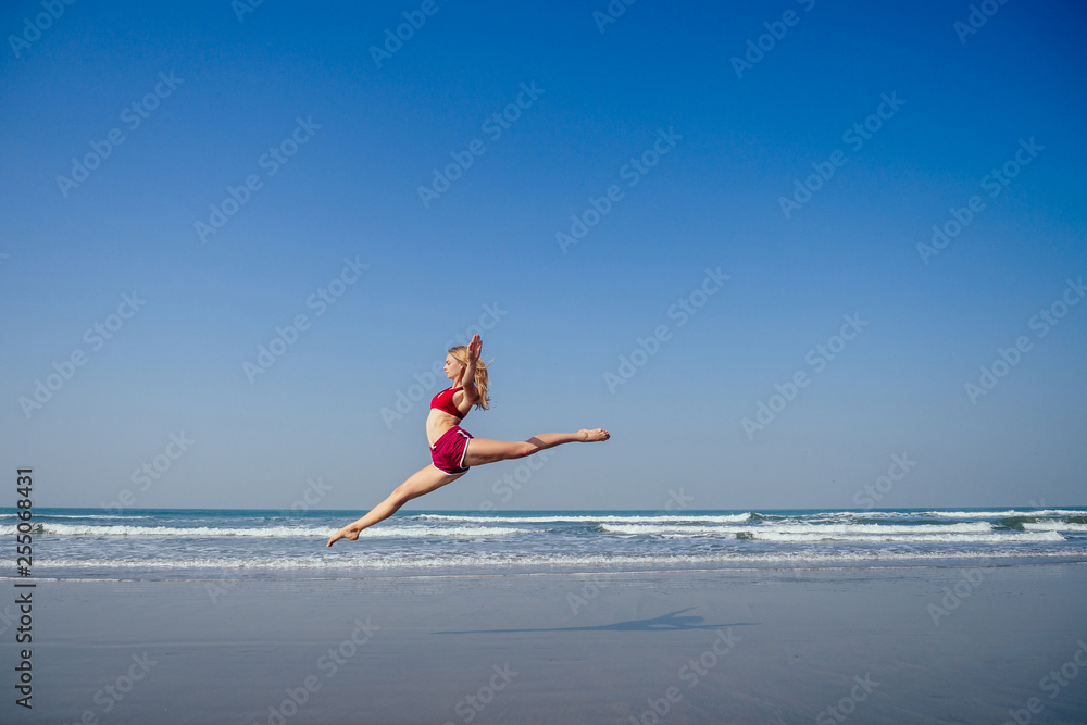Gymnast girl doing splits grand jete in the air. Beautiful young fit
