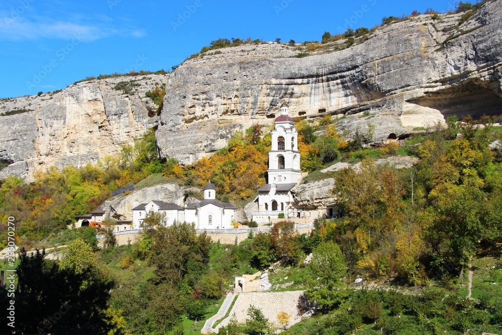 View of one of the temples in the Bakhchisaray Cave Monastery, also known as Assumption Monastery of the Caves, in mid-autumn. Many trees around have already turned yellow.