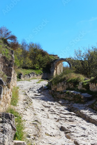 The central street of the cavecity Chufut-Kale. Above the road is visible arch, left from the gate in the fortified wall. It's a medieval city-fortress in the Crimean Mountains that now lies in ruins.