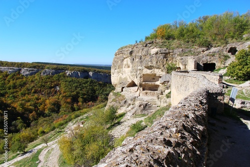 View of cavetown Chufut-Kale above autumn forest in valley near Bakhchisarai city on the Crimean Peninsula. It'is a medieval city-fortress in the Crimean Mountains that now lies in ruins.