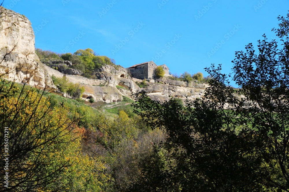 View from the valley on the cavetown Chufut-Kale in the autumn near Bakhchisarai city on the Crimean Peninsula. On the edge of the cliff are kenessas (East European Karaite or Persian synagogue).