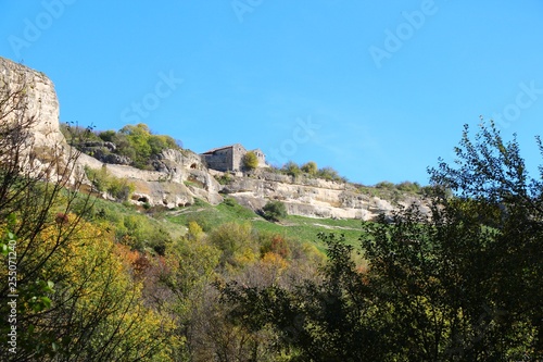 View from the valley on the cavetown Chufut-Kale in the autumn near Bakhchisarai city on the Crimean Peninsula. On the edge of the cliff are kenessas (East European Karaite or Persian synagogue).