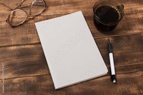 top view image of open notebook with blank pages next to cup of coffee on wooden table. ready for adding text or mockup.