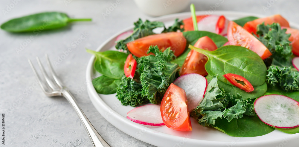 fresh salad of organic spinach, kale, tomatoes and radish with olive oil and lime juice. healthy eating concept. diet, vegan cuisine. light background, selective focus fresh salad of organic spinach, kale, tomatoes and radish with olive oil and lime juice. healthy eating concept. diet, vegan cuisine. light background, selective focus