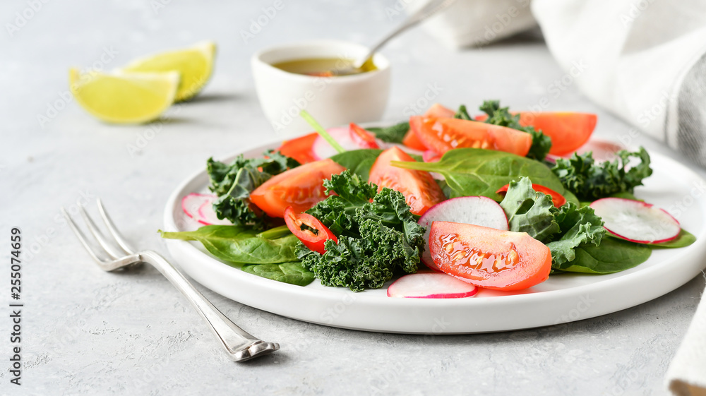 fresh salad of organic spinach, kale, tomatoes and radish with olive oil and lime juice. healthy eating concept. diet, vegan cuisine. light background, selective focus fresh salad of organic spinach, kale, tomatoes and radish with olive oil and lime juice. healthy eating concept. diet, vegan cuisine. light background, selective focus