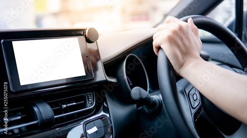 Male driver hand holding on steering wheel using digital dashboard monitor for GPS navigation on the car console in modern car. Urban driving lifestyle with automobile technology