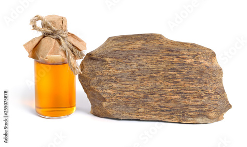 Agarwood, also called aloeswood oudh. With essential oil in pharmaceutical bottle. Isolated on white background photo