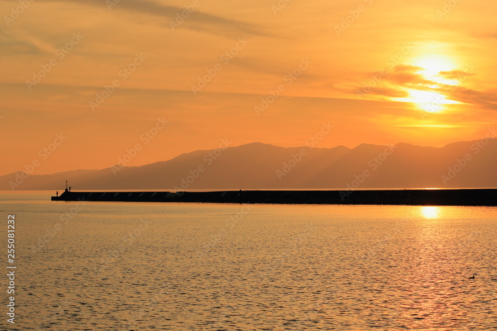 琵琶湖の夕景と突堤の先の釣り人のシルエット