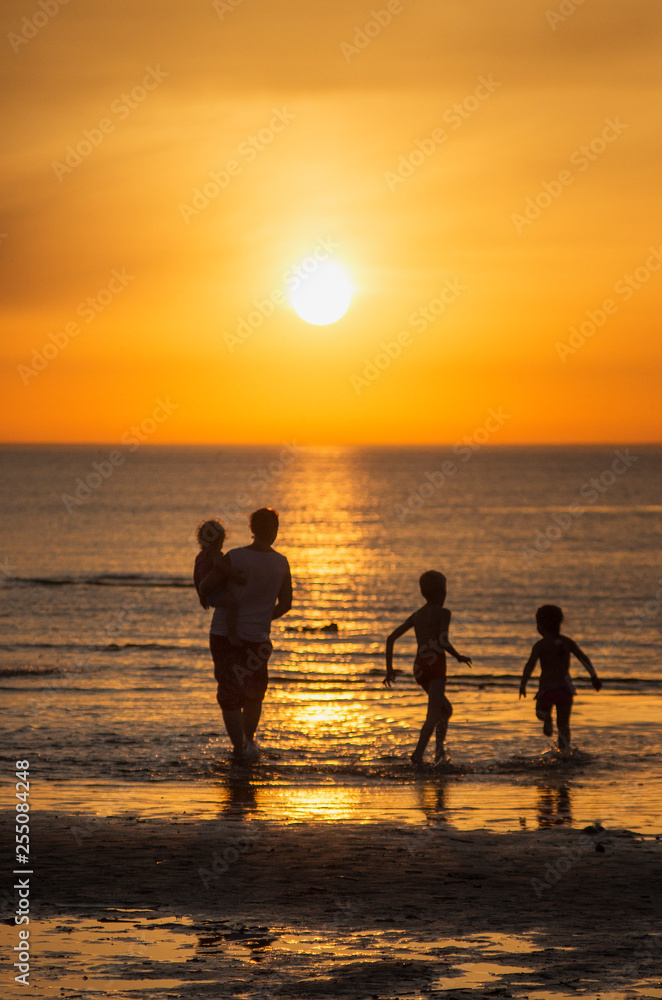 Family resting on the sea. Children play in the sea at sunset.
