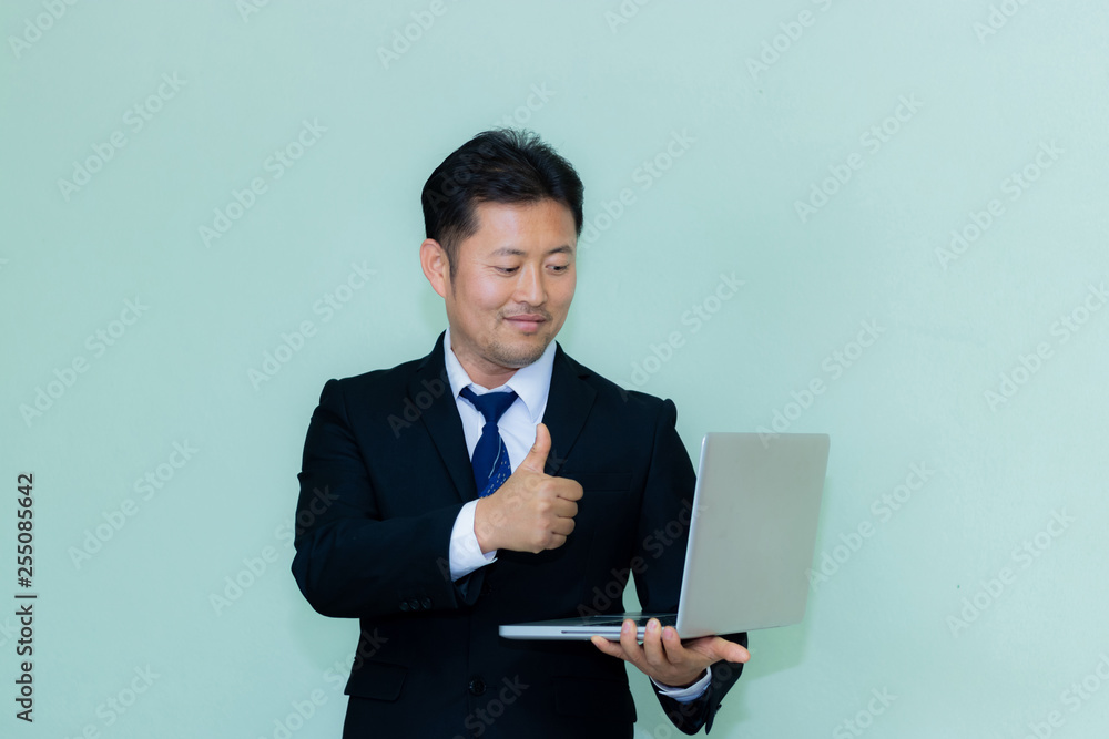 A studio image of an Asian businessman with a handsome beard and hold the tablet a mint green background A studio image of an Asian businessman with a handsome beard and hold the tablet a mint green background