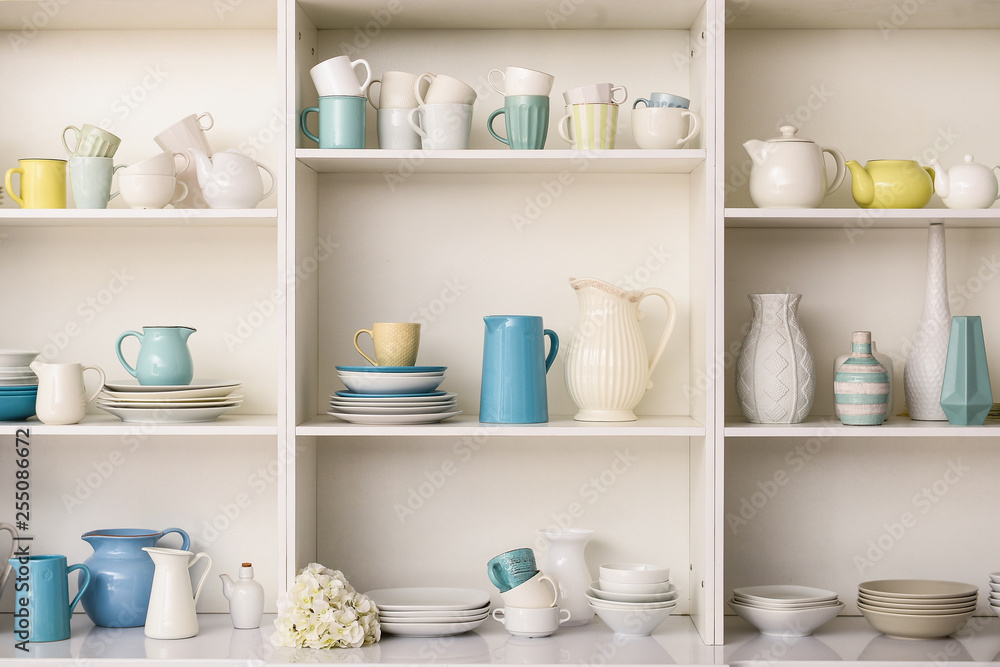 Set of clean dishes on white shelves in kitchen