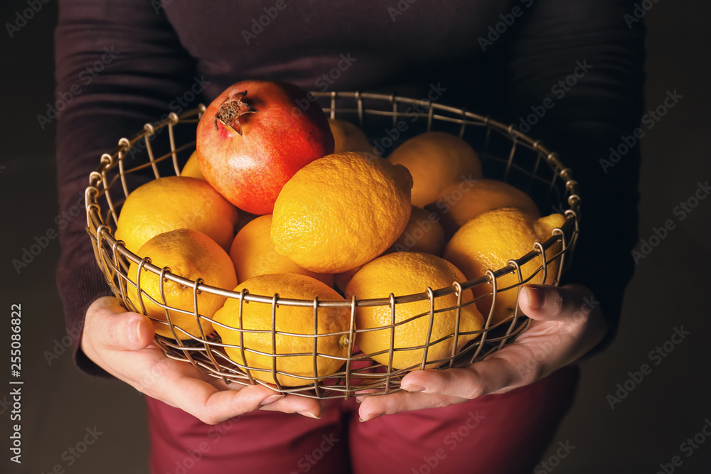 Woman holding basket with fresh fruits, closeup