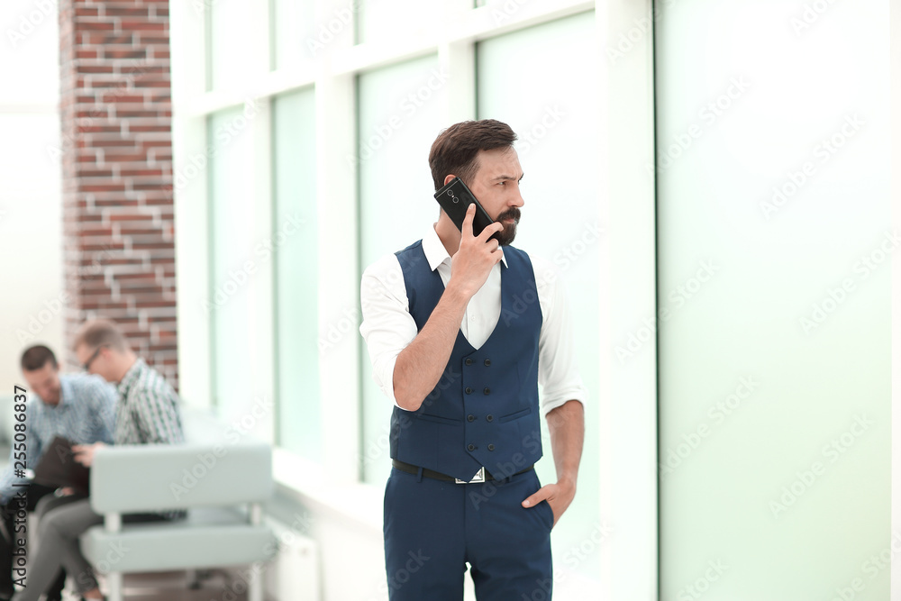 serious businessman talking on mobile phone in office serious businessman talking on mobile phone in office