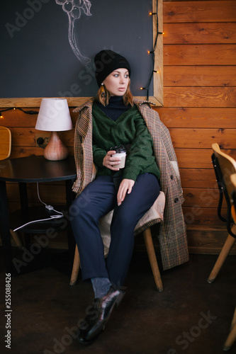 Young beautiful woman wearing fashion clothes sitting in a cafe drinking coffee
