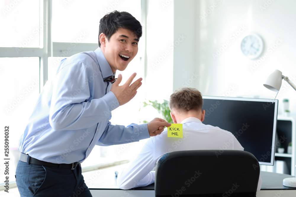 Fototapeta premium Asian man playing a prank on his colleague in office. April Fools' Day prank