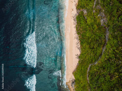 Tropical beach and blue ocean with waves in Bali. Aerial view