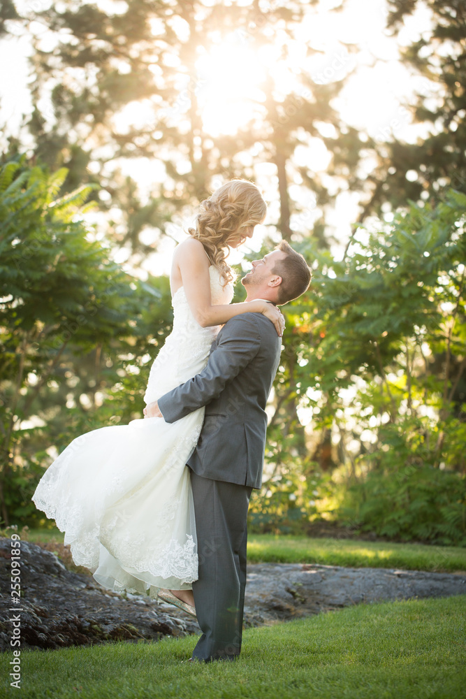 groom lifting beautiful bride on summer wedding day groom lifting beautiful bride on summer wedding day