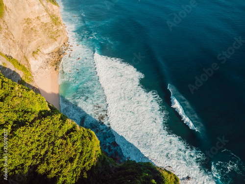 Amazing cliff, beach and blue ocean with waves in Bali. Aerial view